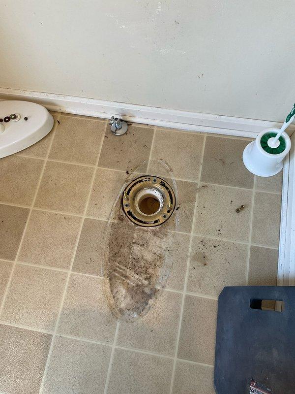 Responded to commercial plumbing service call and assessed multiple repair needs. Documented existing conditions including an improperly located outdoor hose bib installed on bathroom sink ledge and water-damaged flooring surrounding toilet flange with visible staining indicating previous leak or moisture intrusion. Provided estimates for necessary repairs to address code violations and water damage remediation.