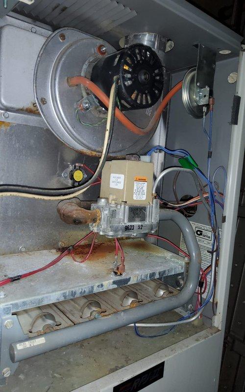 Responded to service call for furnace producing unusual noises with suspected blower motor issue. Upon inspection, accessed furnace cabinet and performed thorough diagnostic evaluation of blower assembly and internal components. Examined blower motor, wheel, and housing for signs of wear, debris accumulation, or mechanical failure. Inspected electrical connections, including motor capacitor leads and wiring harnesses for proper termination and continuity. Evaluated condition of heat exchanger, burner assembly, and gas valve controls. Documented system condition through photographic evidence showing blower wheel configuration, motor mounting, and overall furnace component layout. Noted visible corrosion on burner tubes and general aging of unit, indicating extended service life. Provided customer with findings and recommendations for addressing noise concern and discussed potential repair or replacement options based on equipment age and condition.