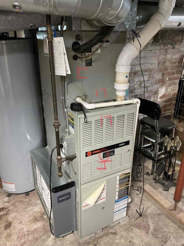 Responded to no heat call and performed comprehensive assessment of existing HVAC system in basement mechanical room. Evaluated aging Trane furnace unit showing signs of wear and operational deficiency, along with associated ductwork, water heater, and plumbing connections. Documented equipment condition through detailed photography, noting furnace specifications, ductwork configuration, and overall system layout. Provided estimate for complete furnace replacement to restore heating functionality to the residence.
