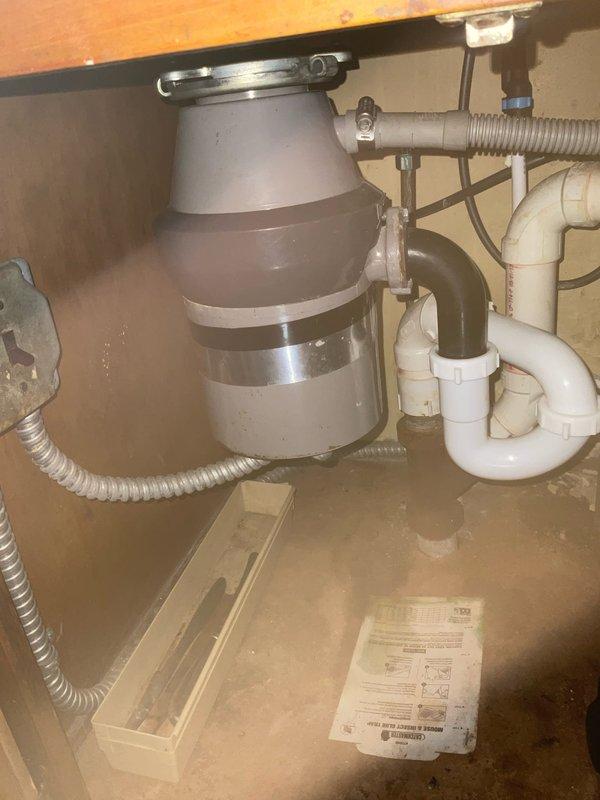 Responded to kitchen sink backup caused by garbage disposal and dishwasher drainage issues. Upon inspection, found improper drainage configuration under kitchen sink with garbage disposal unit connected to dishwasher drain line and P-trap assembly. Cleared blockage in disposal unit and verified proper water flow through drain system. Tested garbage disposal operation and dishwasher drainage cycle to confirm backup was resolved and all fixtures draining properly without further issues.