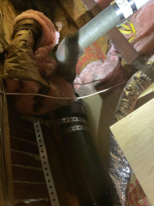 Responded to warranty call for brown water dripping from newly installed plumbing in toddler's bathroom from previous incomplete stacked job. Inspected attic space above bathroom and documented HVAC ductwork, insulation, and plumbing connections. Identified roof leak as source of water intrusion affecting new pipe installation. Photographed affected areas showing flexible aluminum ductwork, PVC pipe connections, exposed framing, and pink fiberglass insulation with visible moisture damage and debris accumulation. Plastic vapor barrier requires re-securing upon completion of repairs.