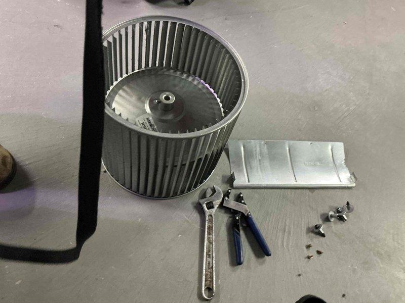 Removed blower assembly from air handler unit and performed thorough cleaning of squirrel cage fan wheel. Blower wheel showed significant dust accumulation on blades which was impacting system airflow and efficiency. Disassembled housing components, extracted blower wheel, and cleaned all debris from blades and assembly. Reinstalled cleaned blower assembly, secured all mounting hardware, and verified proper operation before closing access panel.