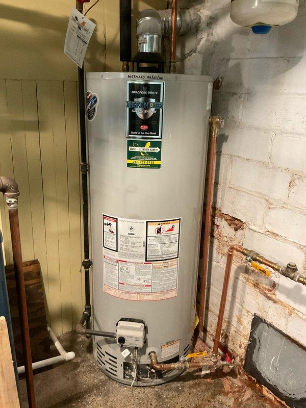 Responded to no hot water complaint at 100-year-old residence with 6-year-old Bradford White water heater installed in March 2020. Upon arrival, performed diagnostic assessment of tanked water heater system including inspection of gas control valve assembly, thermocouple, pilot light operation, and burner functionality. Verified proper operation of copper supply and discharge piping, expansion tank mounted above unit, and isolation valves with yellow handles. Checked drain pan positioning and inspected all visible connections for leaks or corrosion. Tested temperature and pressure relief valve operation and confirmed proper venting configuration. Evaluated water treatment system (Streamax unit) mounted on wall to ensure adequate flow and filtration not impacting heater performance. Inspected gas supply line and control box at base of unit for proper operation. Reset pilot light and verified ignition sequence, confirming burner assembly fired correctly and water heating resumed normal o