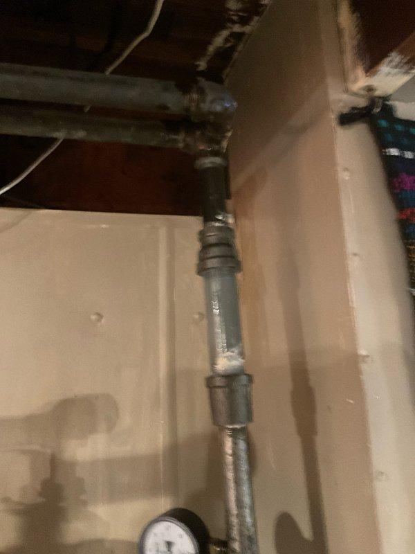 Responded to emergency service call for damaged pipe located above gas meter that had rendered the gas line inoperable. Upon inspection, identified compromised galvanized pipe section with threaded connections in basement utility area requiring immediate replacement. Removed deteriorated pipe segment and installed new pipe section with proper fittings and connections to restore gas line functionality. Verified all joints were properly sealed and tested system integrity to ensure safe operation. Documented existing plumbing configuration including mixed galvanized metal and PVC piping running along exposed wooden joists before completing repairs.