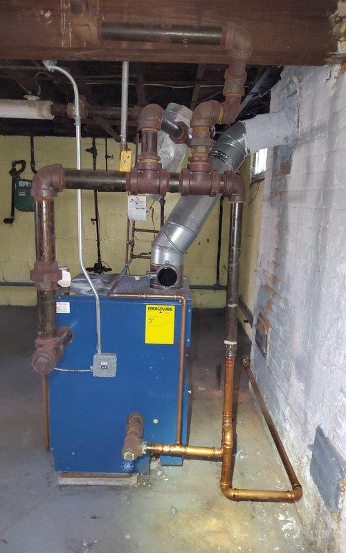 Responded to no heat call on residential boiler system. Upon arrival, found blue cabinet boiler unit in basement with complex piping configuration including copper supply and return lines, expansion tank, and PVC condensate drainage. Performed diagnostic inspection of boiler components including control board, pressure gauges, and safety devices. Verified gas supply, checked electrical connections, and tested ignition sequence. Inspected venting system and condensate drain for proper operation. System restored to normal heating operation. All safety controls verified functional before departure.