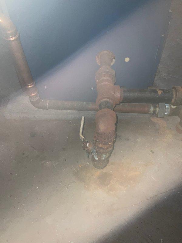 Returned to property to complete revised boiler replacement estimate. Documented existing heating system conditions, including severely corroded piping infrastructure with extensive rust and oxidation on central valve assemblies and horizontal pipe runs. Assessed unfinished basement mechanical space with exposed joists, existing ductwork, and foundation conditions to determine scope of work for new boiler installation and associated piping modifications.