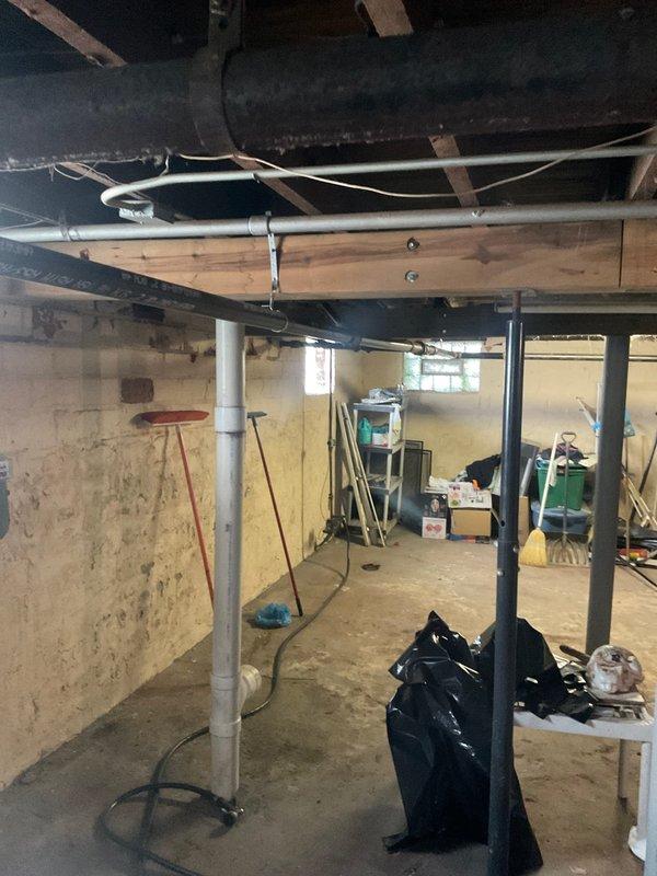 Returned to property to complete revised boiler replacement estimate. Documented existing heating system conditions, including severely corroded piping infrastructure with extensive rust and oxidation on central valve assemblies and horizontal pipe runs. Assessed unfinished basement mechanical space with exposed joists, existing ductwork, and foundation conditions to determine scope of work for new boiler installation and associated piping modifications.