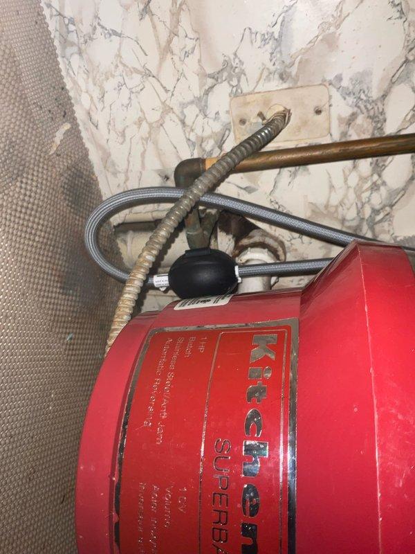 Responded to service call for non-functioning garbage disposal with food debris not draining properly. Upon arrival, assessed the unit located beneath turquoise kitchen sink and determined that the reset button had been previously attempted without success. Inspected disposal unit, cleared jam obstruction, tested motor operation, and verified proper drainage function. Unit restored to full working order with all connections secure and operational.