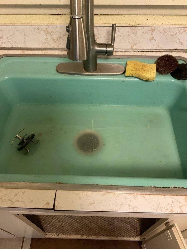 Responded to service call for non-functioning garbage disposal with food debris not draining properly. Upon arrival, assessed the unit located beneath turquoise kitchen sink and determined that the reset button had been previously attempted without success. Inspected disposal unit, cleared jam obstruction, tested motor operation, and verified proper drainage function. Unit restored to full working order with all connections secure and operational.