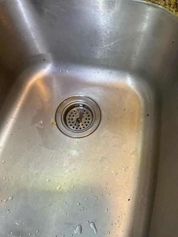 Responded to service call for multiple plumbing issues including two slow-draining sink basins and a leaking kitchen sink. Inspected kitchen sink drain assembly and basin, noting standard strainer configuration with visible mineral deposits and minor staining around drain opening. Assessed plumbing system infrastructure in basement utility area, documenting existing copper supply line configuration with multiple branch connections and main vertical stack. Provided customer with estimate for sump pump battery backup system installation as requested.