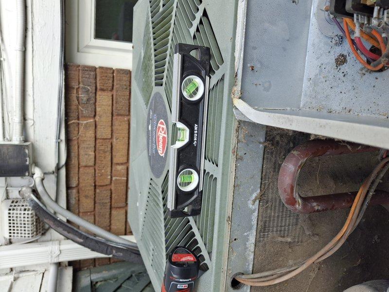 Completed comprehensive air conditioning tune-up on approximately 15-year-old cooling system located in backyard. Verified unit levelness using precision level tool and confirmed condenser pad stability with no signs of settling or sinking. Performed standard maintenance inspection of outdoor condensing unit, checked refrigerant lines, and inspected indoor return air grille for proper airflow.