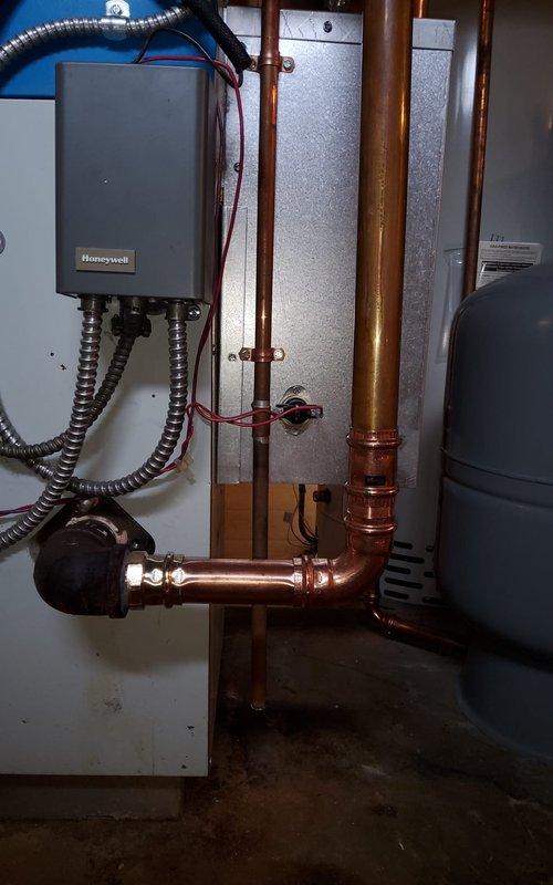 Replaced defective zone valve and damaged 1.25" copper piping section on hydronic heating system. Drained system, installed new zone valve with proper electrical connections to Honeywell control unit, fabricated and soldered copper pipe replacement with appropriate fittings and supports, refilled system, and completed full purge procedure to eliminate air from lines.