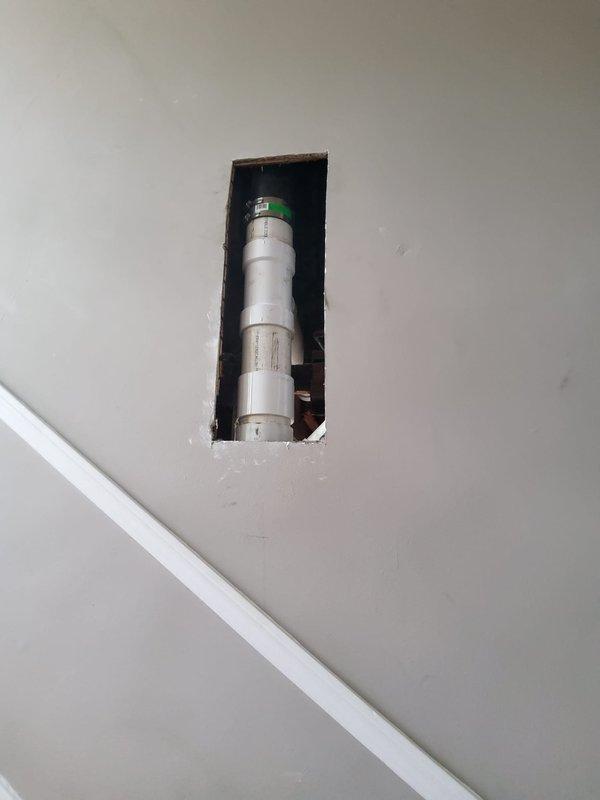 Opened wall in staircase and ceiling in family room to access and expose defective toilet bend. Removed old plumbing components and replaced toilet bend with new PVC piping, extending replacement down through the stack to basement floor level. Installed new first floor toilet bend and tied connection onto existing sink drain line using PVC Y-fitting. Replaced old-style 14-inch rough-in toilet on first floor due to incompatibility with updated plumbing configuration. All new drain and vent piping installed to code specifications with proper slope and connections secured throughout vertical stack system.