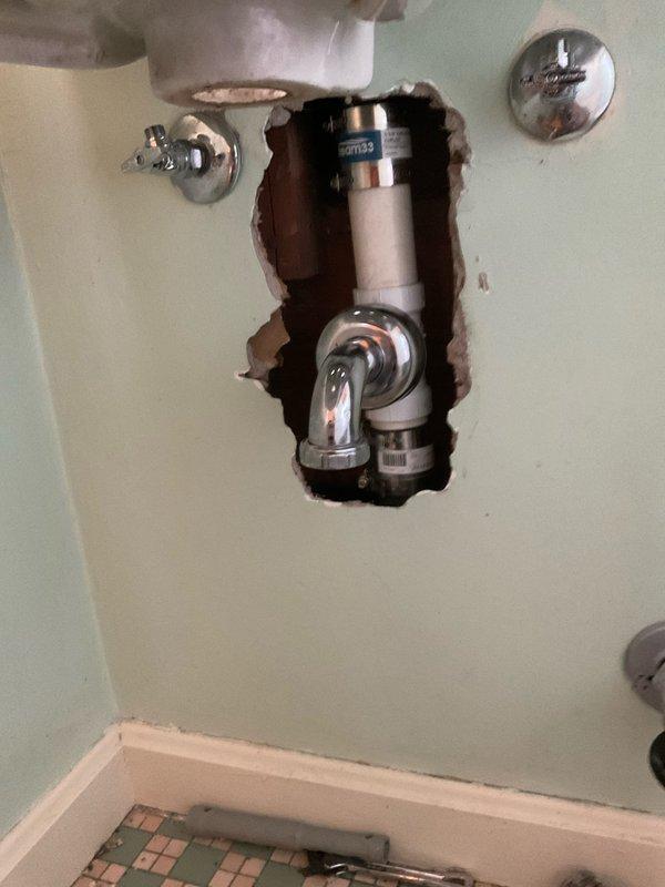 Removed existing two-handle widespread bathroom faucet and replaced with new unit. Installed two new angle stop valves to provide proper water supply control and shutoff capability. Accessed plumbing through wall opening to complete valve installation and ensure proper connections. All supply lines and drainage components verified for proper function and leak-free operation upon completion.