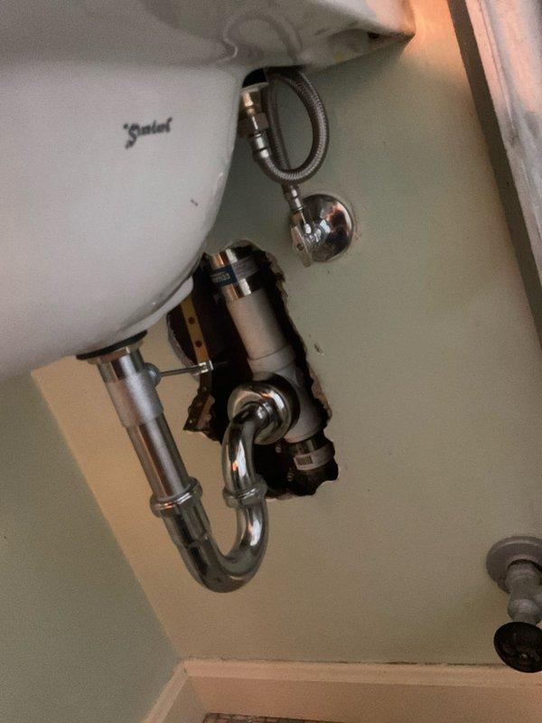 Removed existing two-handle widespread bathroom faucet and replaced with new unit. Installed two new angle stop valves to provide proper water supply control and shutoff capability. Accessed plumbing through wall opening to complete valve installation and ensure proper connections. All supply lines and drainage components verified for proper function and leak-free operation upon completion.