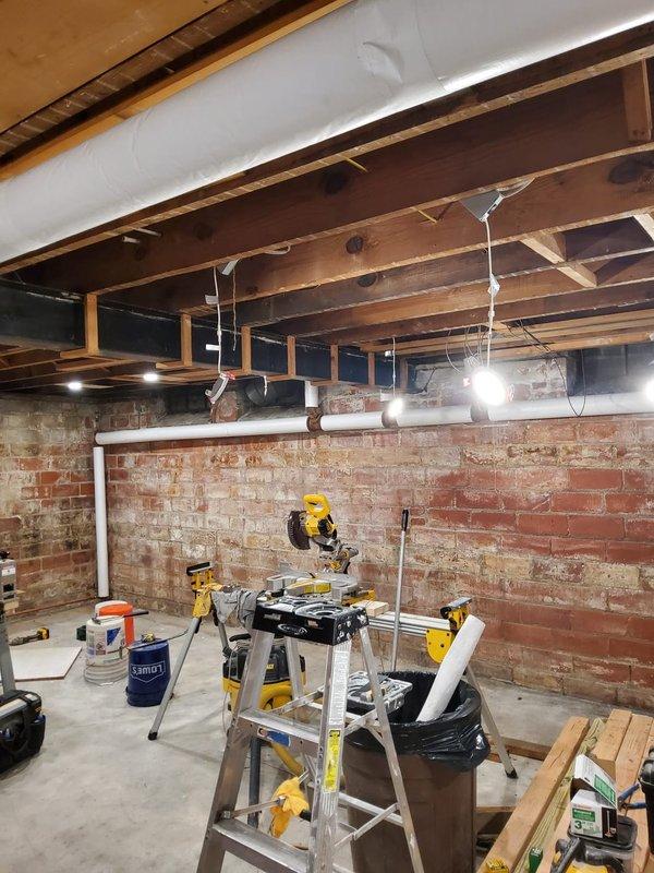 Inspected basement boiler piping system and identified exposed hot water supply and return lines requiring insulation to improve energy efficiency and prevent heat loss. Consulted with property contact regarding insulation specifications and documented current conditions of uninsulated white PVC and gray metal piping running through exposed ceiling joists above unfinished basement area. Recommended proper pipe insulation installation to meet code requirements and optimize system performance.