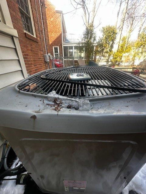 Responded to insurance diagnostic request for 20-year-old Carrier WeatherMaker Infinity air conditioning system reportedly damaged by falling ice block. Performed visual inspection and photographic documentation of outdoor condenser unit, noting weathered condition consistent with age, accumulated debris on fan grille, and rust spots on casing and corners. Assessed top-mounted fan assembly, grille integrity, and motor housing for impact damage, documenting findings for insurance claim purposes.