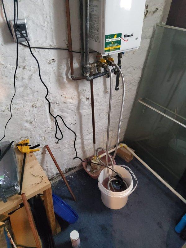 Performed descaling maintenance service on a Rinnai tankless natural gas water heater to remove mineral buildup and restore optimal efficiency. Isolated the unit using shut-off valves, connected descaling pump with hoses and buckets containing descaling solution, circulated the solution through the heat exchanger to dissolve scale deposits, flushed the system thoroughly, and verified proper operation upon completion.