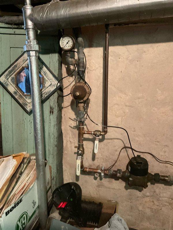 Responded to service call regarding water shut-off valve issue identified by water department. Inspected main water line shut-off valve assembly and associated plumbing components in basement mechanical room. Documented existing conditions of aged copper piping, pressure gauges, shut-off valves, and circulation system connections, noting signs of wear and patina on copper surfaces. Advised customer that water line repair or replacement at shut-off valve location would be required as indicated by municipal water department inspection.