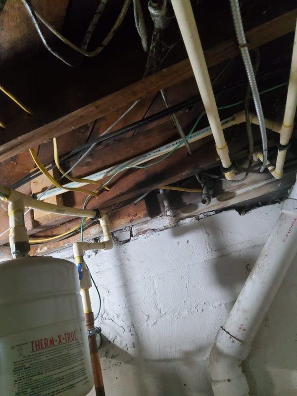 Completed comprehensive plumbing assessment of basement utility area, documenting existing plumbing infrastructure including PVC supply and drain lines, pipe routing through floor joists, and overall system condition. Photographed all accessible plumbing components, pipe connections, and support installations to provide customer with detailed visual documentation of current plumbing configuration for future reference and maintenance planning.