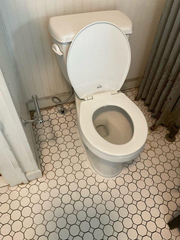 Installed a standard round front Gerber toilet in bathroom with octagonal tile flooring. Repaired the closet flange to ensure proper seal and stability before setting the new fixture. Connected water supply line and verified proper function and flush operation.