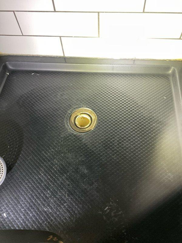 Responded to a clogged shower drain in a 110-year-old residential property. Upon arrival, assessed the black textured shower pan with center brass drain fixture and determined the blockage was preventing proper drainage. Cleared the obstruction using appropriate drain clearing tools and techniques, restoring full water flow through the drain system. Tested the drain thoroughly to ensure complete functionality and documented the completed work with photographs of the shower base and surrounding white subway tile installation.