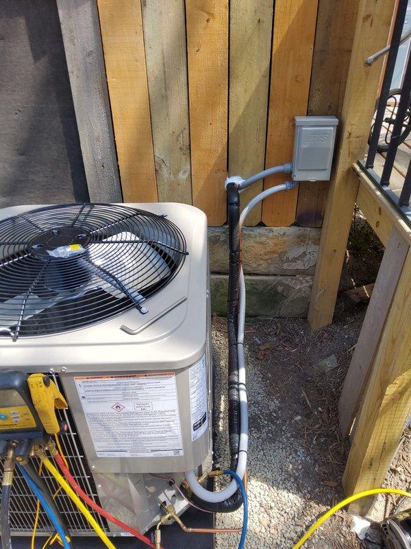 Completed add-on air conditioning installation to existing forced-air heating system. Disconnected and repositioned existing Carrier furnace, rerouted return air ducting to draw from both sides of unit to accommodate new evaporator coil mounted on top of furnace. Installed outdoor condenser unit at rear of property with refrigerant line set, electrical disconnect, and PVC conduit for power supply connection. Evaluated second-floor bathroom airflow concerns and provided recommendations for improved duct distribution. System ready for final electrical connection by outside contractor.