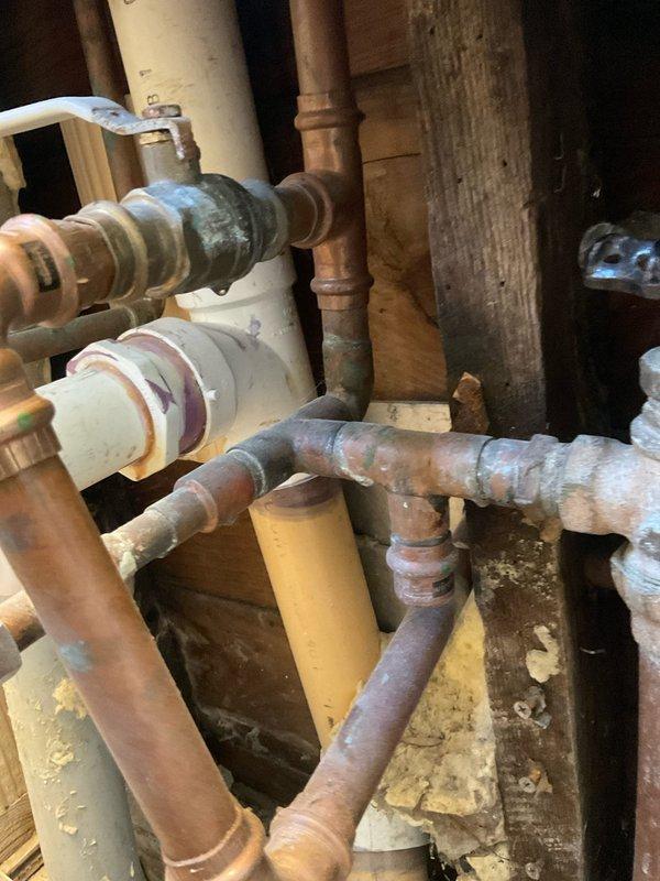 Responded to emergency water leak at 31-year-old residential property where homeowner reported significant water accumulation described as a "small lake." Upon arrival, accessed crawl space and identified active leak in aging copper plumbing system showing extensive corrosion and oxidation throughout multiple pipe sections and fittings. Located source of leak at deteriorated connection point where corroded copper piping met PVC drainage assembly near floor joists. 

Shut off water supply using existing valve system and assessed full extent of damage to plumbing infrastructure. Multiple sections of copper piping displayed advanced patina, surface oxidation, and compromised integrity due to age of installation. Replaced failed section of copper pipe and corroded fittings with new materials, ensuring proper connections between existing copper lines and PVC drainage system. Applied appropriate primer and secured all joints to prevent future leakage. Tested system under pressure to verify r
