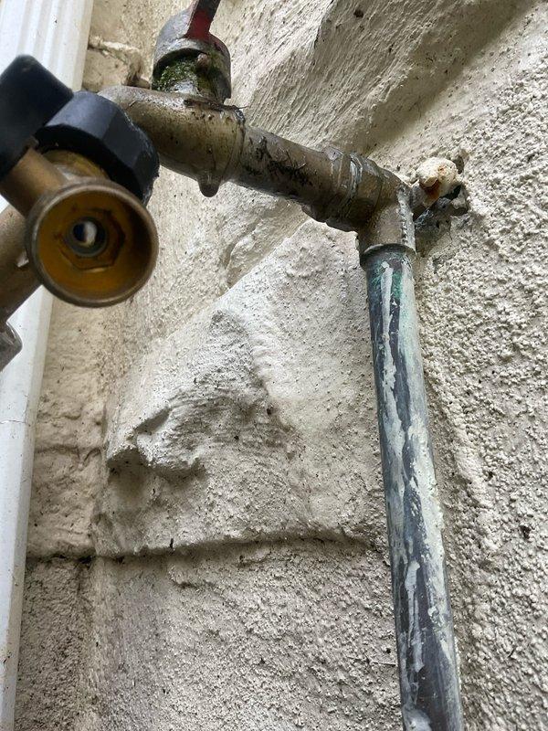 Responded to service call for possible gas line connection issue to outdoor gas grill at century-old residential property. Upon arrival, conducted thorough visual inspection of exterior gas piping system and connections. Located gas supply line running along exterior wall with visible aged brass fittings and weathered piping showing signs of corrosion and environmental exposure. Performed comprehensive gas leak detection testing at all connection points, joints, and fittings using leak detection solution. Inspected gas line routing from building to grill connection point, noting deteriorated condition of exterior plumbing infrastructure consistent with age of home. Verified gas pressure at supply line and tested system integrity. Documented existing conditions of gas piping assembly, fittings, and connection points with photographs for service records. All testing completed to ensure safe gas delivery to outdoor appliance connection.