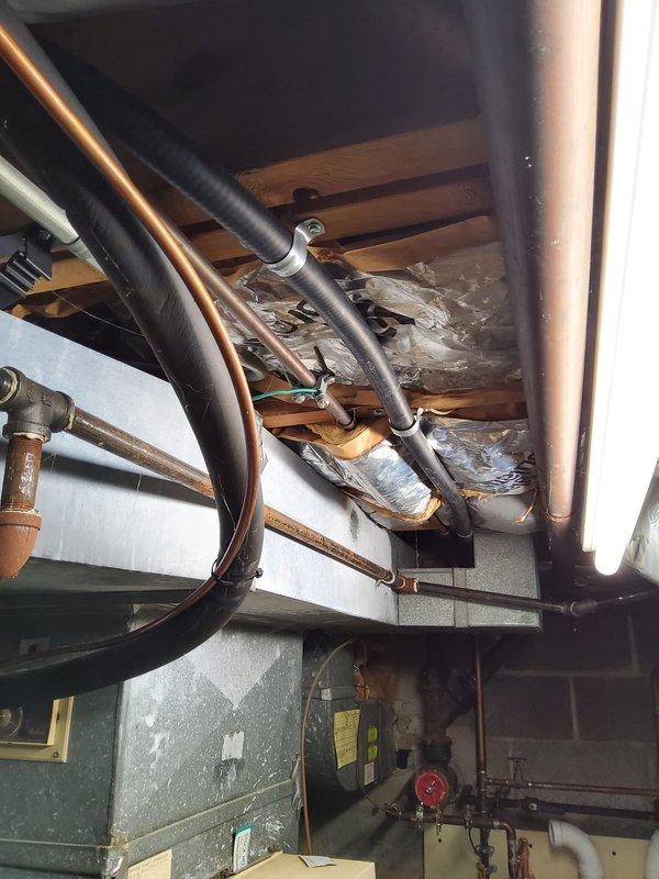 Completed installation of wall-mounted tankless water heater system in basement utility area, including full copper pipe connections, integrated expansion tank, and proper venting with PVC exhaust piping. All plumbing connections were secured to code specifications, unit was mounted on plywood backing board against concrete block wall, and system was tested and confirmed operational.