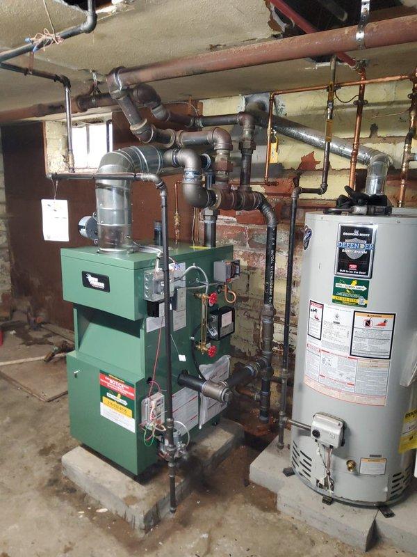Completed full installation of New Yorker steam boiler model CGs50C in basement mechanical room. Installation included new automatic water feeder, low water cutoff safety control, sight glass assembly, pressure control, programmable thermostat, and backflow preventer. All near boiler piping was modified and updated to accommodate the new unit, including copper supply lines, steam distribution piping, and multiple shut-off valves for system control and maintenance access.