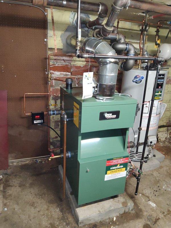 Completed full installation of New Yorker steam boiler model CGs50C in basement mechanical room. Installation included new automatic water feeder, low water cutoff safety control, sight glass assembly, pressure control, programmable thermostat, and backflow preventer. All near boiler piping was modified and updated to accommodate the new unit, including copper supply lines, steam distribution piping, and multiple shut-off valves for system control and maintenance access.