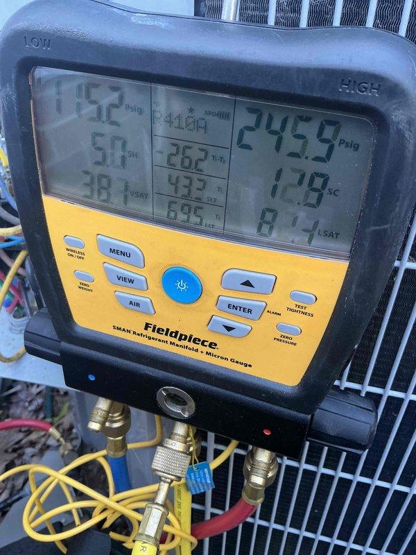 Performed comprehensive preemptive air conditioning tune-up and maintenance on outdoor condensing unit during off-season winter period. Connected digital manifold gauges to service ports and recorded system pressures and temperatures, with high-side pressure reading 245.9 psig and multiple temperature measurements including 117.8°F and 84.7°F to establish baseline performance metrics. Completed full preventive maintenance inspection of unit located in confined space between building and fence line, ensuring system readiness for upcoming cooling season.