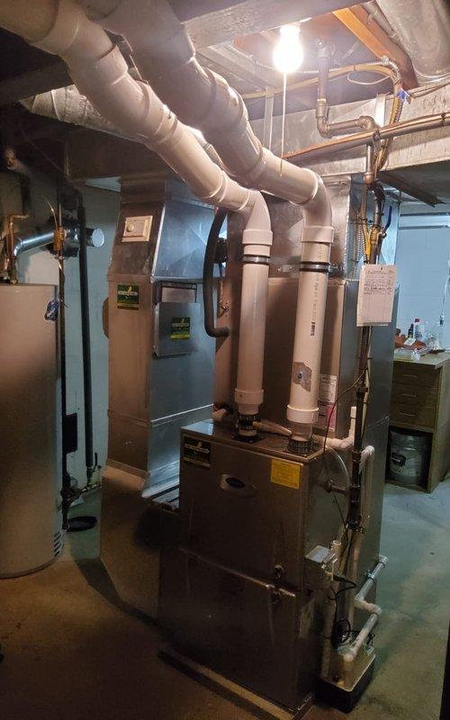 Completed annual maintenance on 12-year-old residential air conditioning system. Performed comprehensive tune-up including inspection of indoor furnace unit and outdoor condensing unit, verified proper operation of all components, and documented equipment condition with photographs showing both basement mechanical room and exterior AC unit in satisfactory working order.