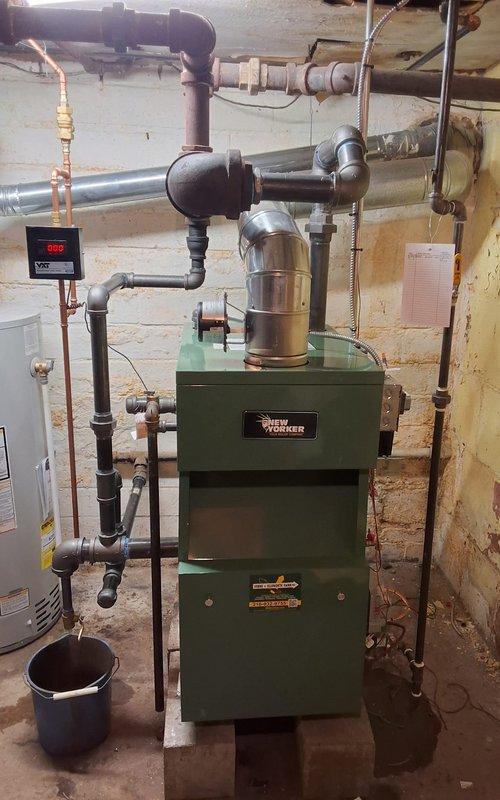 Completed full steam boiler replacement, installing a New Yorker model CGS50C steam gas boiler with all required safety and control components. Installation included new automatic water feeder, low water cutoff, sight glass, pressure control, and programmable thermostat for improved system efficiency and monitoring. All near boiler piping was modified to meet current code requirements, and a new backflow preventer was installed to protect the potable water supply. Additionally, replaced the existing water heater with a Bradford White 40-gallon residential unit, complete with proper venting and copper supply line connections. Both units were tested, verified for proper operation, and left in full working condition.