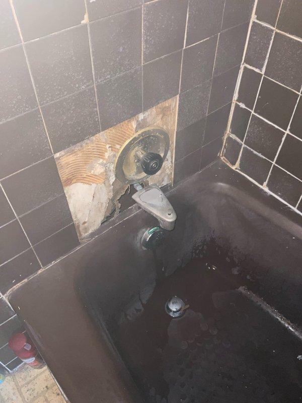 Responded to customer report of dripping shower fixture. Upon inspection, found leaking tub/shower valve requiring access through tile wall. Removed section of wall tile to expose valve assembly and plumbing connections. Identified source of leak at valve stem or cartridge. Additionally inspected toilet tank components and found aging flush valve and fill valve assembly with mineral buildup and deterioration. Documented existing conditions with photographs for customer records and repair recommendations.