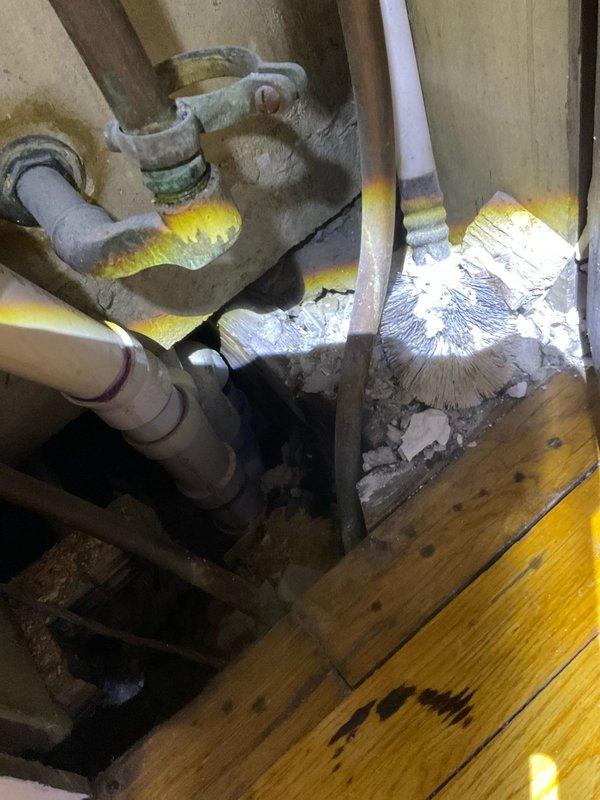 Responded to ceiling leak complaint in century-old home with unknown source. Conducted thorough investigation by accessing crawl space beneath affected area, inspecting plumbing infrastructure including aging metal pipes, corroded valves, white PVC piping, and associated fittings surrounded by fiberglass insulation. Traced potential leak sources through multiple pipe runs and joist cavities to identify origin point. Documented findings with photographic evidence of plumbing configuration and affected interior space for reference and further remediation planning.
