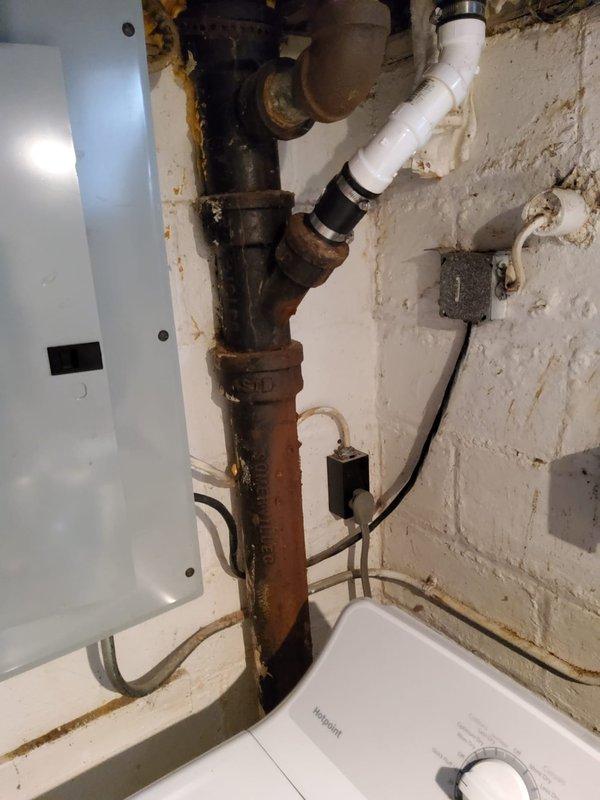 Completed comprehensive plumbing assessment of utility area as requested. Inspection revealed extensive corrosion and deterioration on vertical metal supply piping, with significant rust staining and surface degradation requiring attention. Documented mixed-age plumbing installation featuring corroded metal components connected to newer PVC piping via rubber coupling sleeves, along with moisture exposure affecting adjacent ductwork and mechanical components.