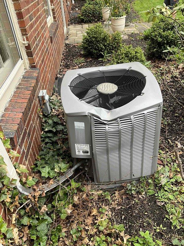 Completed on-site evaluation for residential air conditioning system replacement. Assessed existing outdoor condenser unit positioned adjacent to brick exterior, noting equipment age, condition, and installation parameters. Documented current system specifications, electrical connections, and clearance requirements for replacement unit sizing and installation planning. Photographed equipment nameplate data and surrounding landscape conditions to determine optimal placement and access considerations for new system installation.