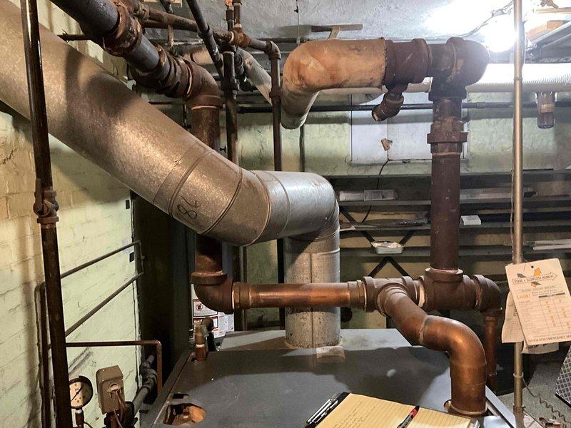 Conducted comprehensive assessment of existing steam boiler system for replacement estimate. Evaluated aged copper piping network showing significant corrosion and oxidation throughout mechanical room, documented condition of interconnected plumbing components including multiple elbow joints and T-connections. Inspected associated radiator system per customer inquiry and photographed current boiler installation, piping configuration, and basement mechanical infrastructure to provide accurate replacement specifications.