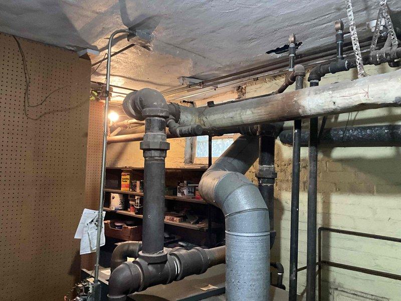 Conducted comprehensive assessment of existing steam boiler system for replacement estimate. Evaluated aged copper piping network showing significant corrosion and oxidation throughout mechanical room, documented condition of interconnected plumbing components including multiple elbow joints and T-connections. Inspected associated radiator system per customer inquiry and photographed current boiler installation, piping configuration, and basement mechanical infrastructure to provide accurate replacement specifications.