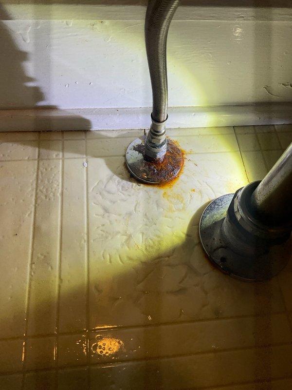 Responded to service call for multiple water leaks throughout the property. Repaired leaking outside spigot at exterior foundation, replaced faulty hot water shut-off valve under kitchen sink, and addressed leaking waterline connection at bathroom sink. Photographic documentation revealed corroded pipe fittings with visible rust staining and water damage at appliance base, indicating prolonged moisture exposure. Exterior inspection showed insulated pipes along foundation with exposed copper section requiring attention. All leak sources were identified, connections were secured or replaced as needed, and water flow was restored to proper operating condition.