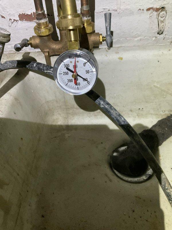 Responded to callback for water heater installation with reported basement water leakage. Upon inspection, confirmed system was operating at approximately 60 PSI without proper pressure regulation. Identified missing pressure reducing valve and thermal expansion tank from original installation, both critical components for safe water heater operation and code compliance. Documented existing corroded plumbing infrastructure and deteriorated pressure relief valve assembly showing significant oxidation and mineral buildup. Photographed current system configuration including pressure gauge readings and condition of existing brass fittings and copper piping. Explained to customer the necessity of installing pressure regulator to protect water heater from excessive incoming water pressure and expansion tank to accommodate thermal expansion, preventing potential system failure and water damage. Recommended immediate installation of both components to bring system into compliance and resolve l