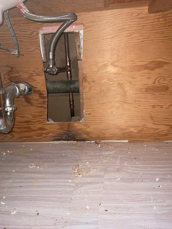 Installed water supply line components through floor access opening, including 2 3/8" threaded angle stop valve and 1/2" compression fitting. Connected flexible braided metal supply hose to brass fittings using two 3/8" brass nipples of varying lengths (4"-6") to complete the water supply connection. All connections were secured and tested for proper operation.
