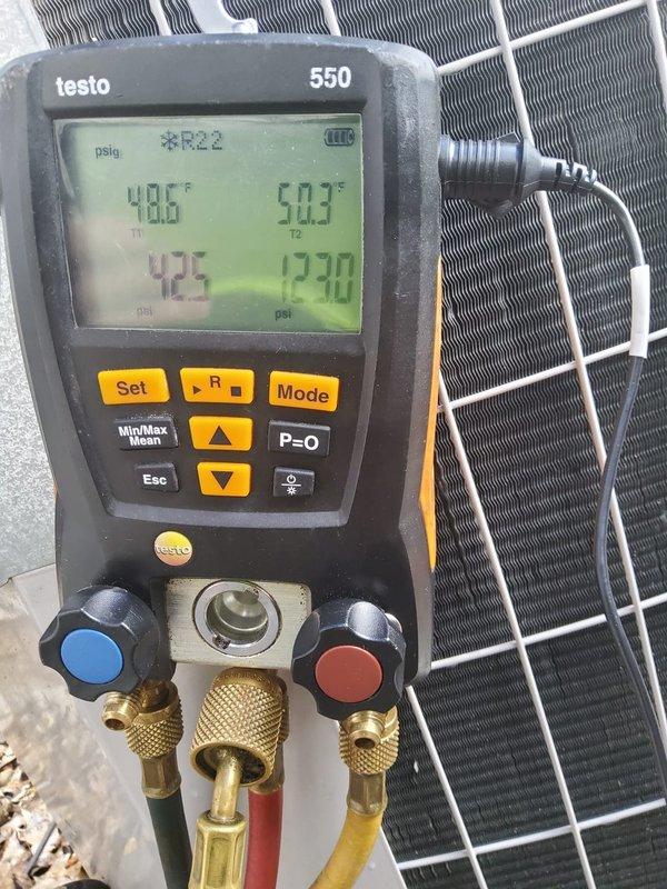 # HVAC Maintenance - Cooling System Service

Performed comprehensive AC tune-up on residential cooling system utilizing R22 refrigerant. Connected Testo 550 digital manifold gauges to measure system pressures and temperatures, recording suction pressure of 42.5 psi and discharge pressure of 270 psi with temperatures reading 48.6°F and 50.3°F. Inspected outdoor condensing unit including condenser coil condition through protective mesh guard, verified unit was mounted properly on concrete pad.

Examined electrical connections at terminal block, noting multiple wire connections including yellow/black striped, blue, pink/red, and white wires properly secured to brass screw terminals with appropriate crimped connectors. Observed typical dust and debris accumulation on electrical components and mounting surfaces consistent with system age and operation. Inspected capacitor and associated wiring configuration for proper connections and secure mounting.

System currently operating within norma