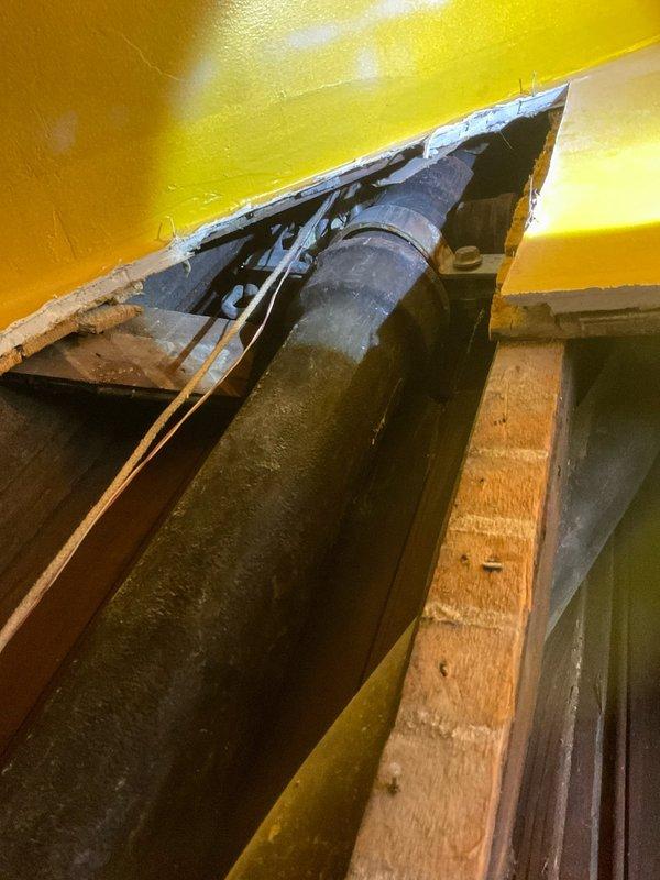 Responded to emergency call for leaking stack pipe in residential property. Upon arrival, accessed wall cavity through existing opening in yellow-painted wall to inspect vertical plumbing stack and associated piping. Investigation revealed severely corroded cast iron stack pipe with active leak point. Documented extensive deterioration of metal components including heavy rust accumulation, oxidation, and structural compromise of threaded connections at base of stack. Assessed surrounding mechanical systems and framing for water damage. Photographed corroded piping, deteriorated fittings, and compromised stack assembly to document extent of failure. Provided recommendations for stack replacement due to advanced age and corrosion throughout affected section.