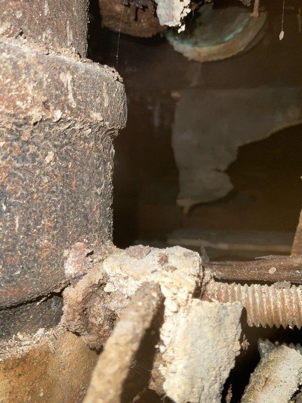 Responded to emergency call for leaking stack pipe in residential property. Upon arrival, accessed wall cavity through existing opening in yellow-painted wall to inspect vertical plumbing stack and associated piping. Investigation revealed severely corroded cast iron stack pipe with active leak point. Documented extensive deterioration of metal components including heavy rust accumulation, oxidation, and structural compromise of threaded connections at base of stack. Assessed surrounding mechanical systems and framing for water damage. Photographed corroded piping, deteriorated fittings, and compromised stack assembly to document extent of failure. Provided recommendations for stack replacement due to advanced age and corrosion throughout affected section.