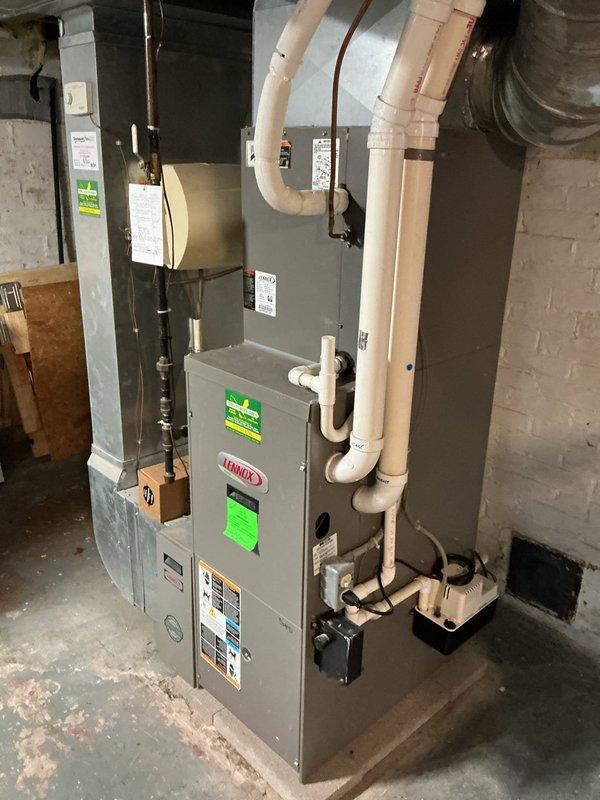 Responded to no-heat service call for non-operational furnace in basement. Upon inspection, confirmed existing Lennox furnace unit was not turning on and determined equipment had reached end of service life based on age and condition. Marked unit for replacement and documented existing installation configuration including white PVC condensate piping, copper refrigerant lines, electrical panel connections, and metal ductwork connections. Photographed current system layout showing furnace positioning, venting arrangement, drainage setup with black condensate pump, and electrical service panel for reference during replacement planning. Provided estimate for complete furnace replacement to restore heating functionality to residence.