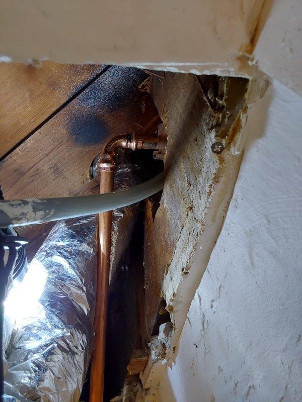 Responded to assessment request for potential water line damage. Investigated ceiling and wall cavity to determine if copper water line was compromised during previous HVAC installation or if damage resulted from pipe failure. Accessed mechanical chase through existing opening in drywall to inspect copper plumbing and insulated ductwork. Documented condition of exposed piping, structural framing, and surrounding building materials showing water staining and deterioration. Photographed copper pipe routing, insulated HVAC components, and damaged wall surfaces for warranty evaluation and determination of cause.