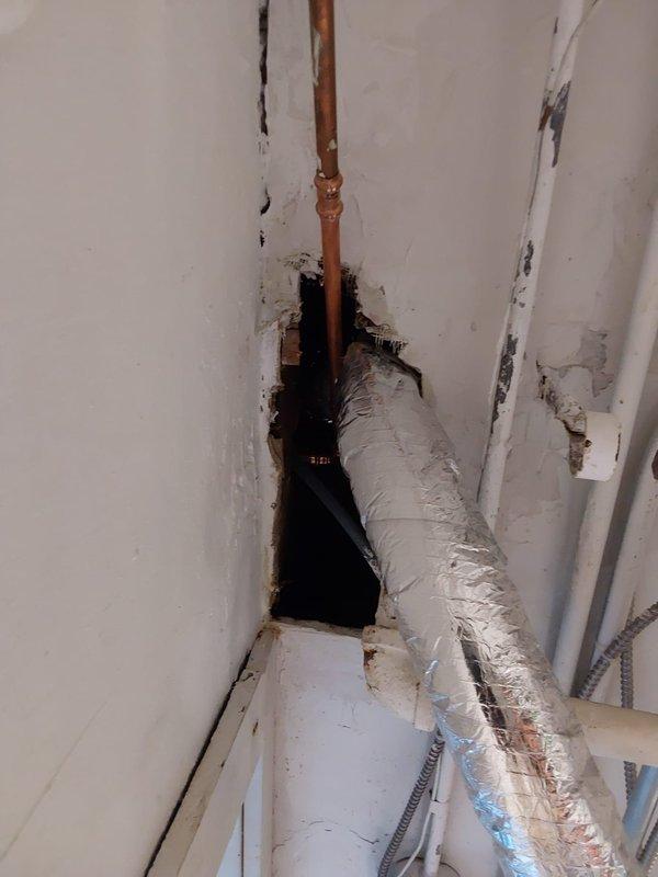 Responded to assessment request for potential water line damage. Investigated ceiling and wall cavity to determine if copper water line was compromised during previous HVAC installation or if damage resulted from pipe failure. Accessed mechanical chase through existing opening in drywall to inspect copper plumbing and insulated ductwork. Documented condition of exposed piping, structural framing, and surrounding building materials showing water staining and deterioration. Photographed copper pipe routing, insulated HVAC components, and damaged wall surfaces for warranty evaluation and determination of cause.